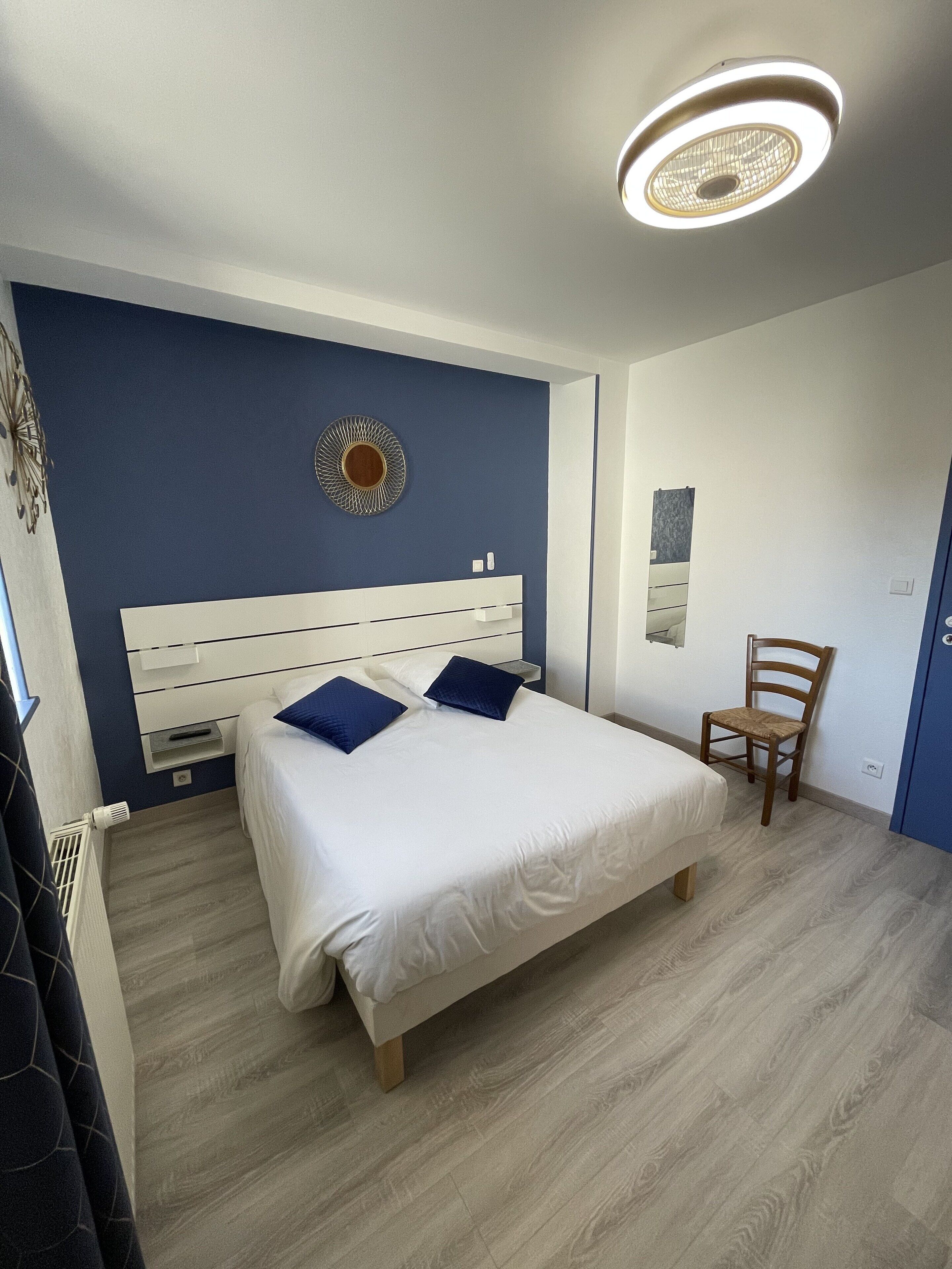 Une chambre à coucher avec un lit, une chaise, une horloge murale et un luminaire au plafond.