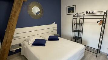 A bedroom with a bed, a wooden ladder, a mirror, and a metal rack.