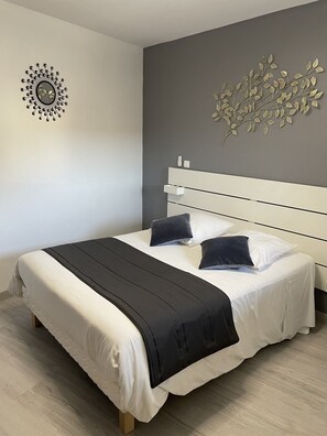Ein modernes Schlafzimmer mit einem großen Bett, einem weißen Kopfteil und einem dekorativen Wandbild.