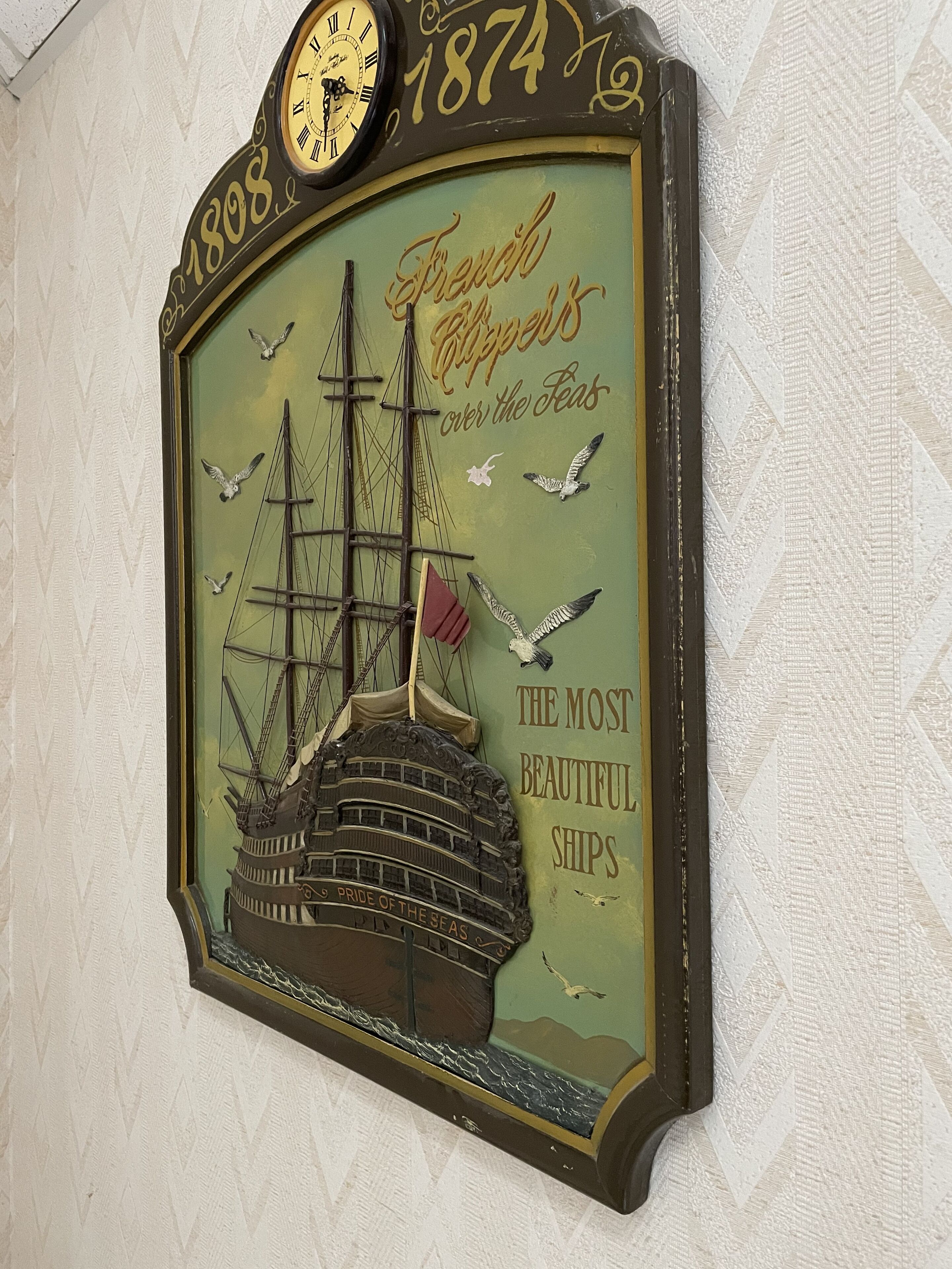 A wall clock with a vintage design, featuring a ship and the year 1874.