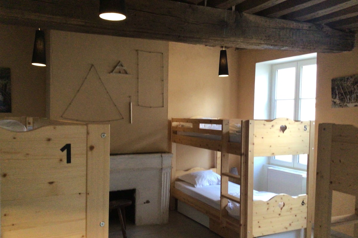 A bunk bed room with a desk, a hanging light fixture, and a window.