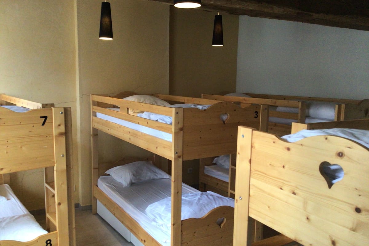 A dormitory room with bunk beds, numbered 7, 8, and 3, and two pendant lights.