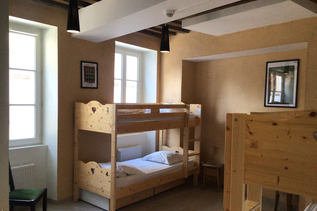 A bunk bed room with a chair and a small table.
