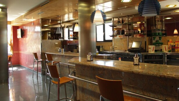 A modern bar area with a marble countertop, metal chairs, and pendant lighting. - Hostal Tio Pepe II (Bembibre)