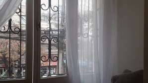 A room with a large window featuring wrought iron bars and sheer white curtains. A plush chair is positioned near the window. - Atacama Backpackers (Santiago)