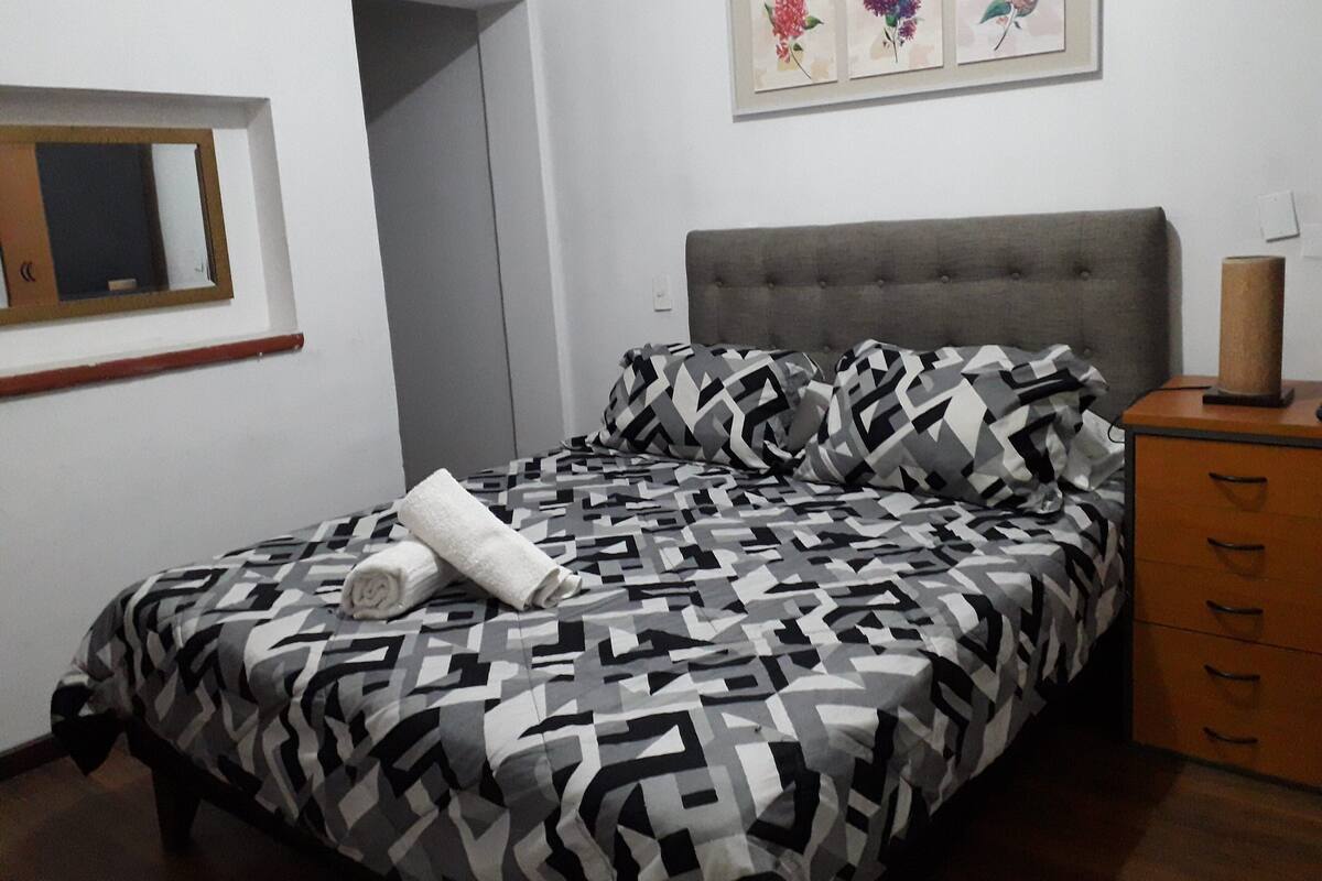 A bedroom with a bed, a dresser, a mirror, and a door.