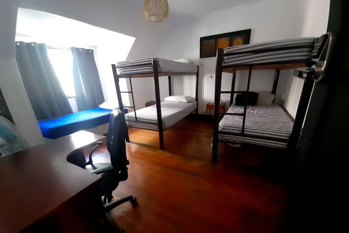 A dormitory room with bunk beds, a desk, and a chair.