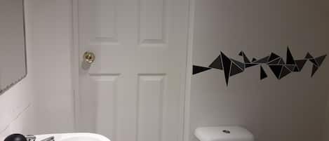 Un baño con un lavabo blanco, un inodoro y una puerta con picaporte.