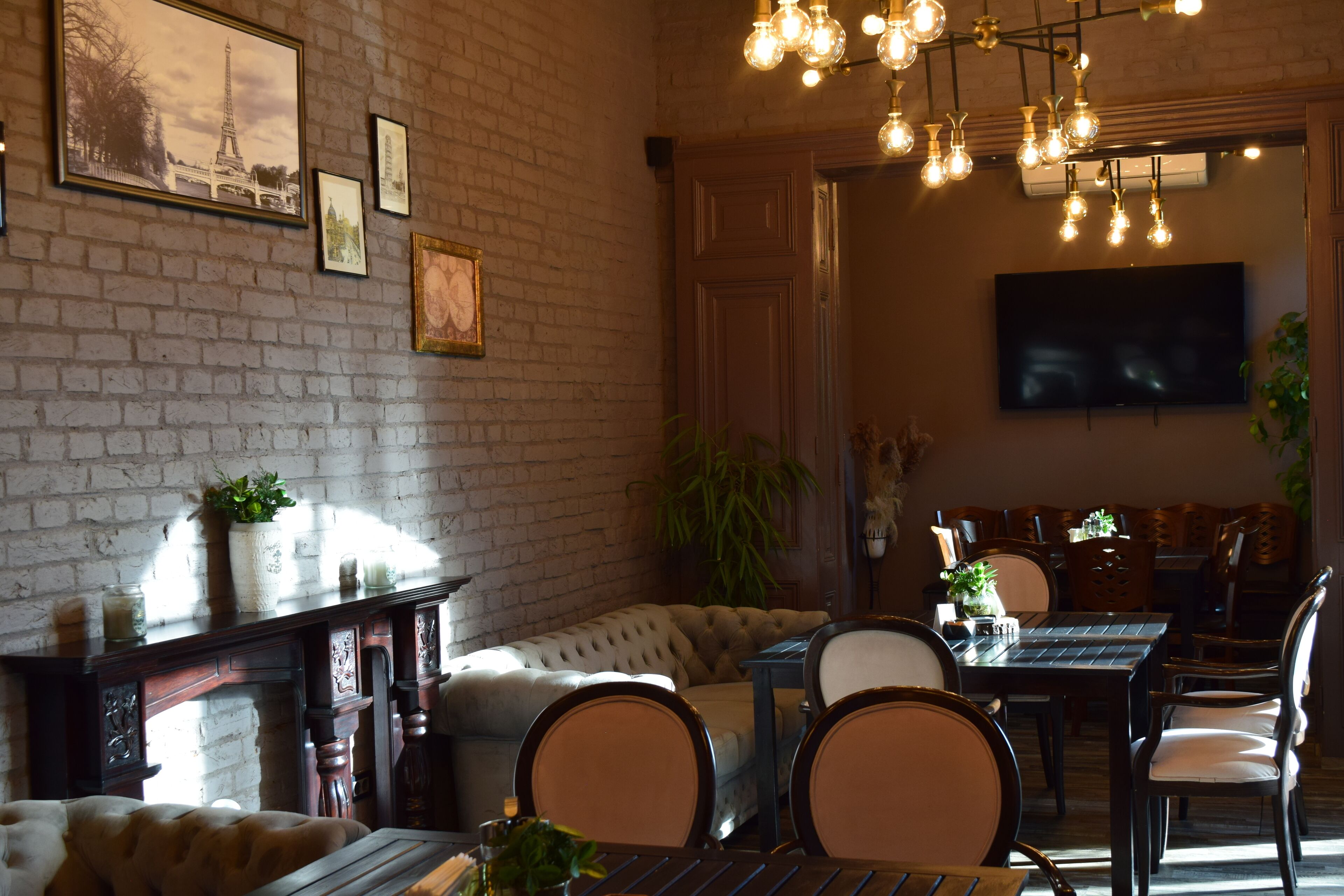 A cozy dining area with a brick wall, a sofa, and a TV mounted on the wall.