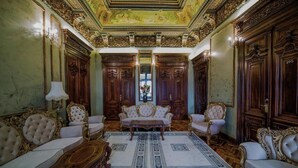 A luxurious room with ornate wood paneling, a large central sofa, and a patterned rug. - Hotel Boutique 5 Continents (Craiova)