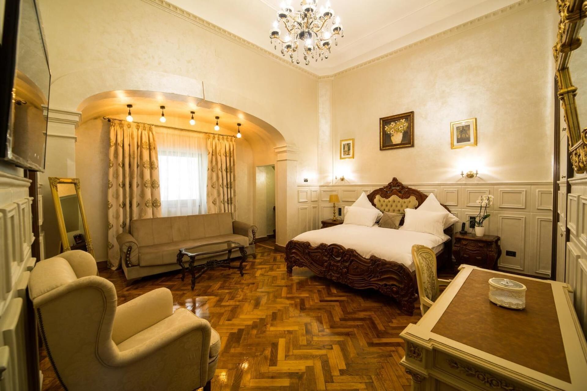 A spacious bedroom with a large bed, a sofa, a chair, and a small table.