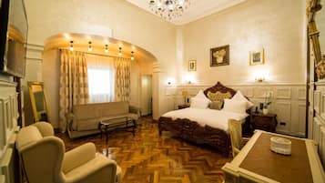 A spacious bedroom with a large bed, a sofa, a chair, and a small table.