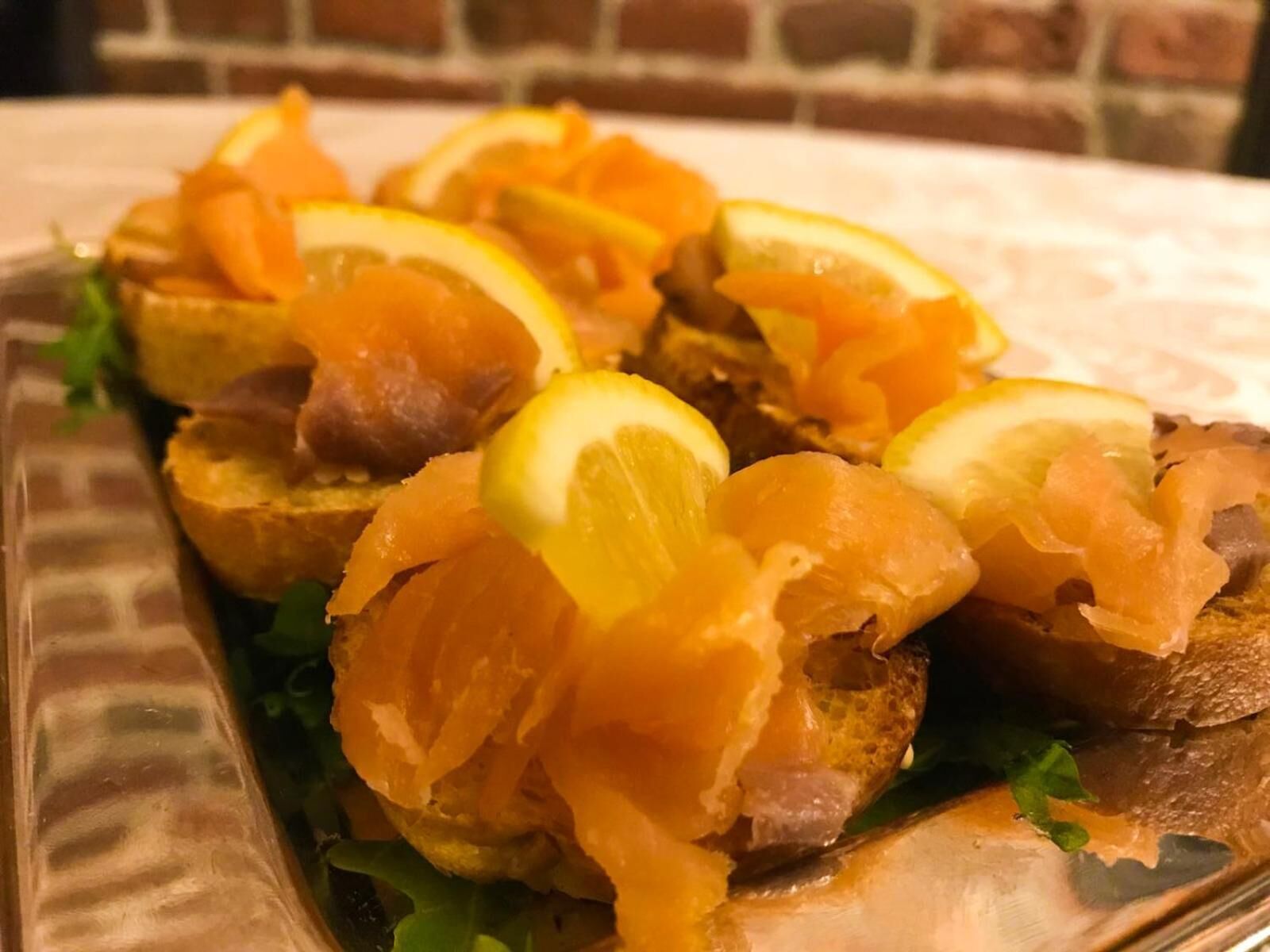 A dish with bread, salmon, and lemon slices.