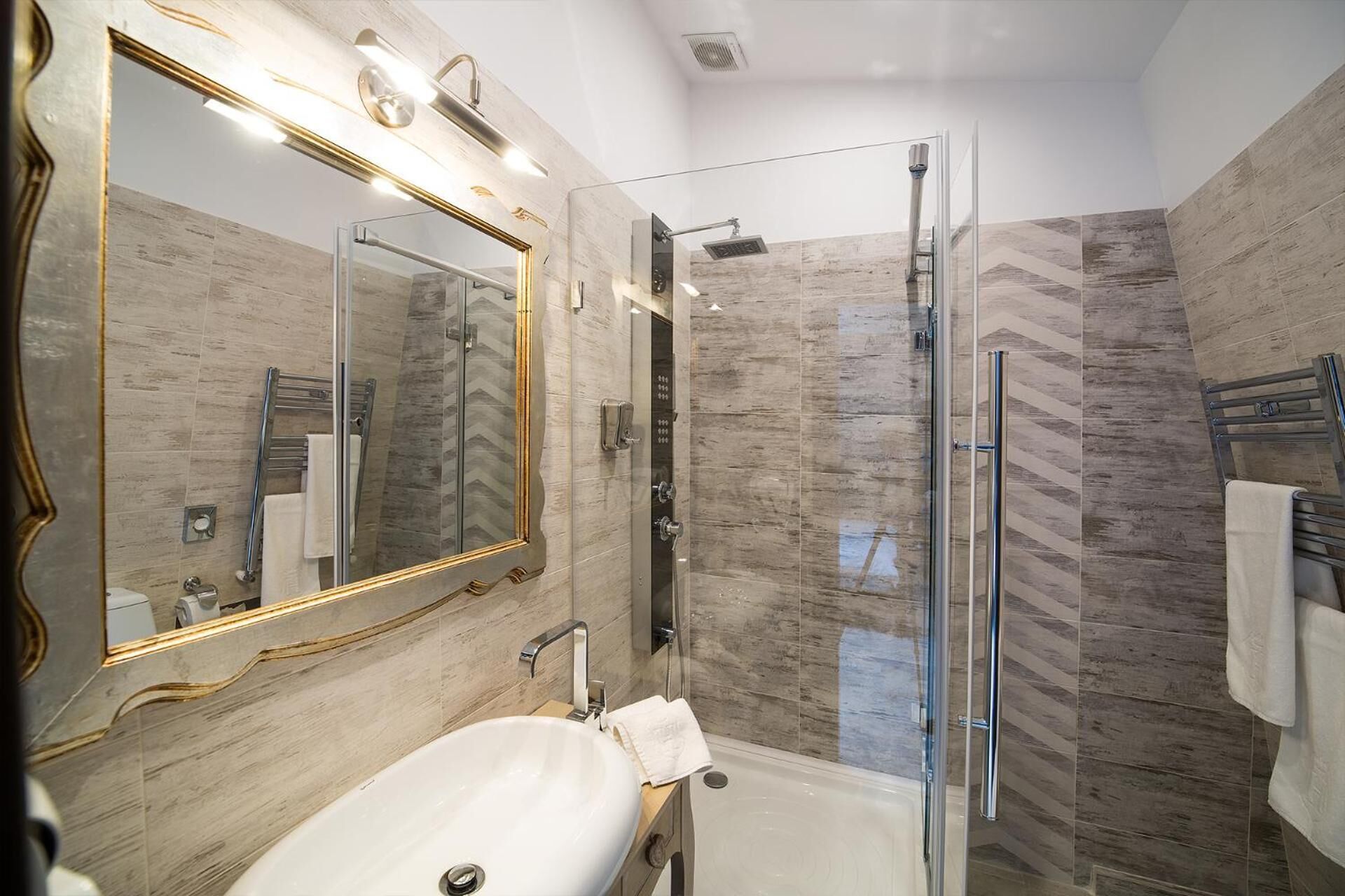 A modern bathroom with a large mirror, a glass shower enclosure, and a white sink.