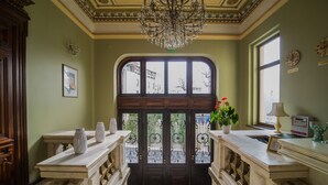 A grand entrance with a chandelier, a large arched window, and a door with decorative ironwork. - Hotel Boutique 5 Continents (Craiova)