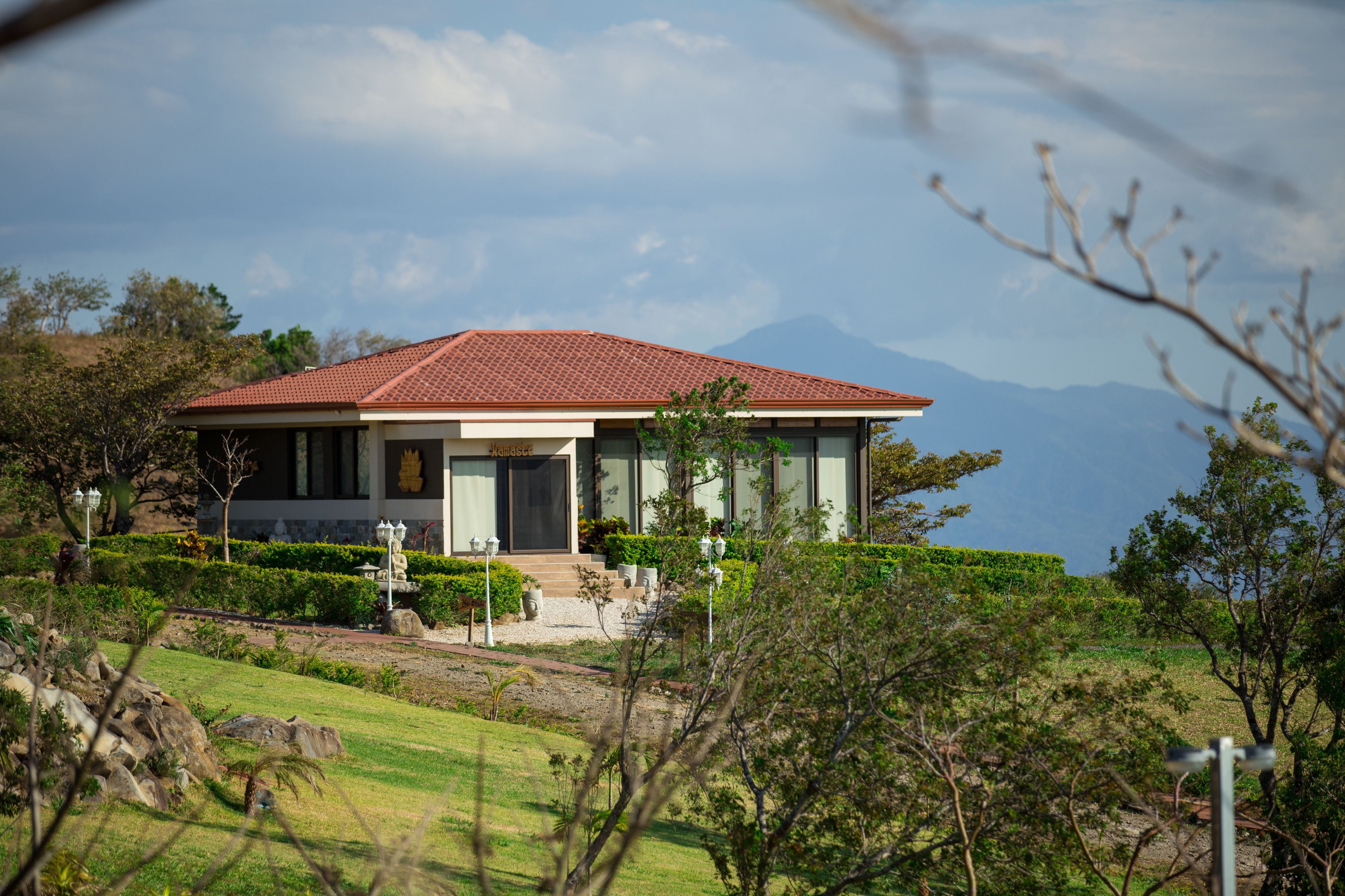 A modern house with a red roof, large windows, and a well-maintained garden.