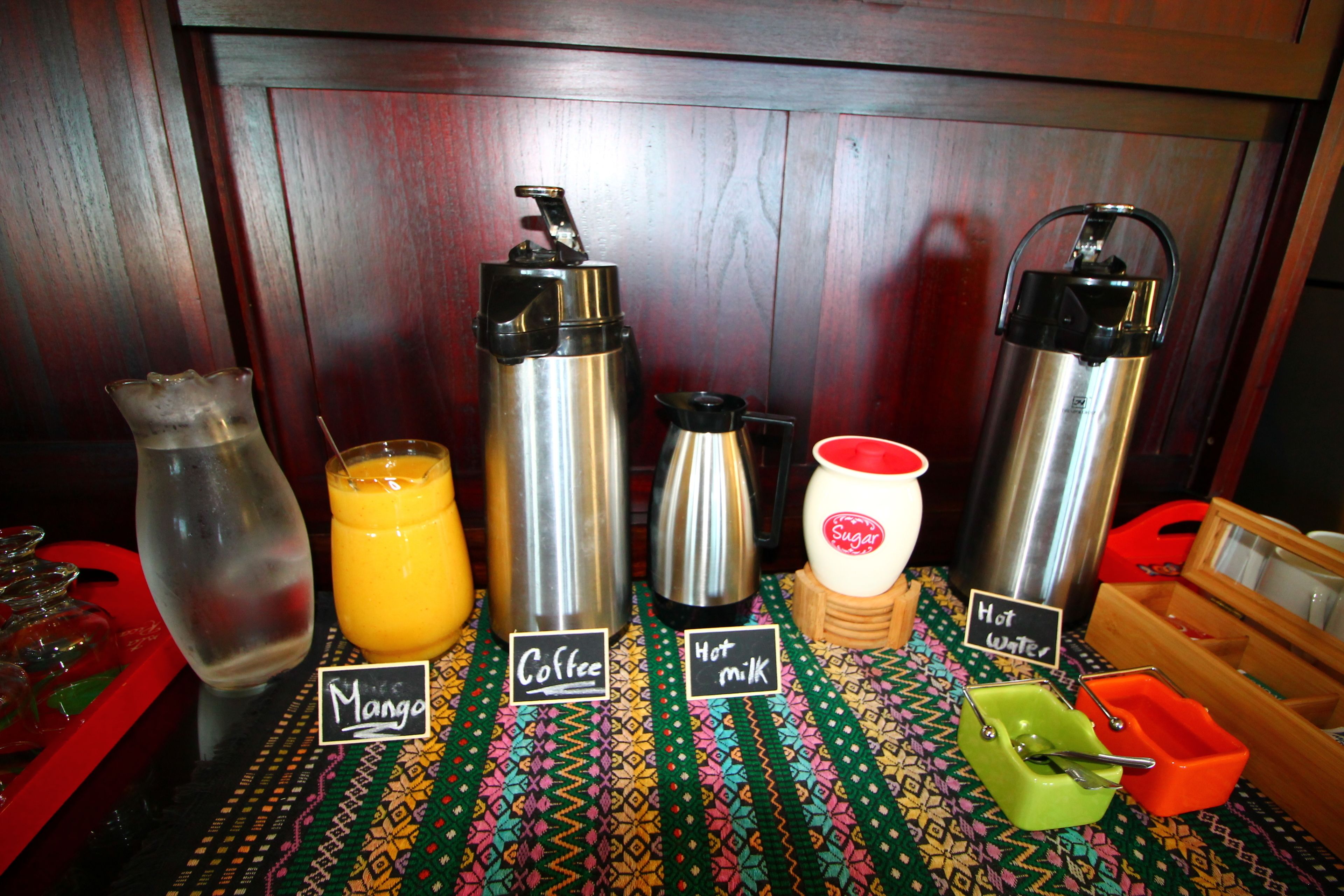 A breakfast setup with labeled containers for mango, coffee, hot milk, and hot water.