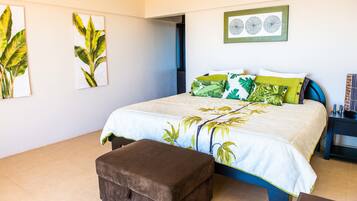 A bedroom with a bed, a bench, and artwork on the walls.