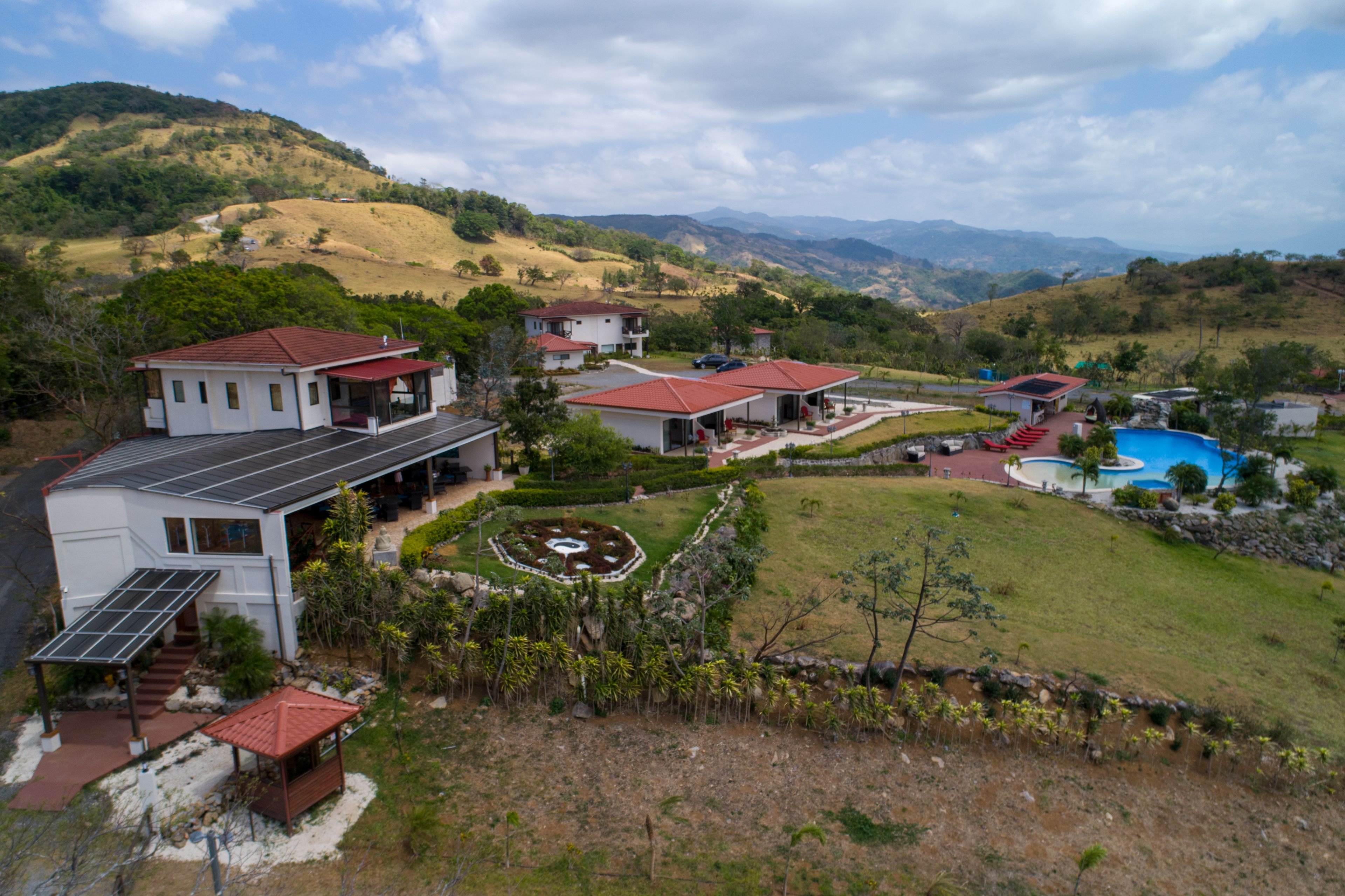 A residential area with houses, a swimming pool, and a hilly landscape.