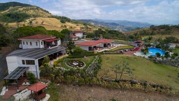 A residential area with houses, a swimming pool, and a hilly landscape.