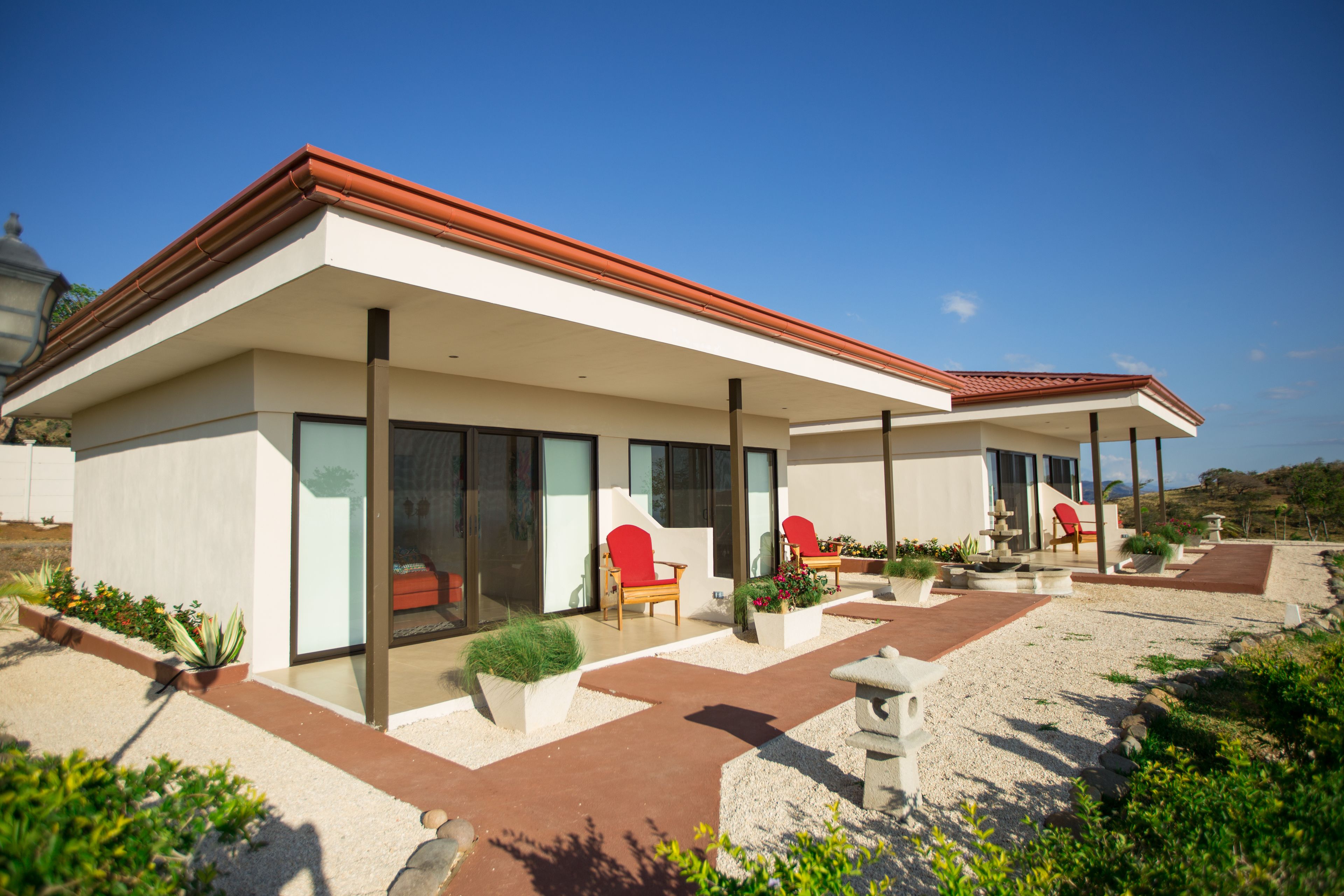 Une maison moderne dotée d’un patio couvert, d’un espace salon extérieur et d’un jardin.