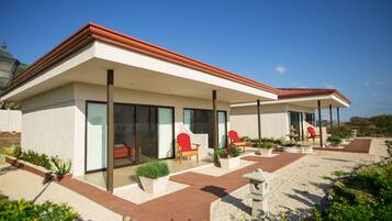 Une maison moderne dotée d’un patio couvert, d’un espace salon extérieur et d’un jardin.