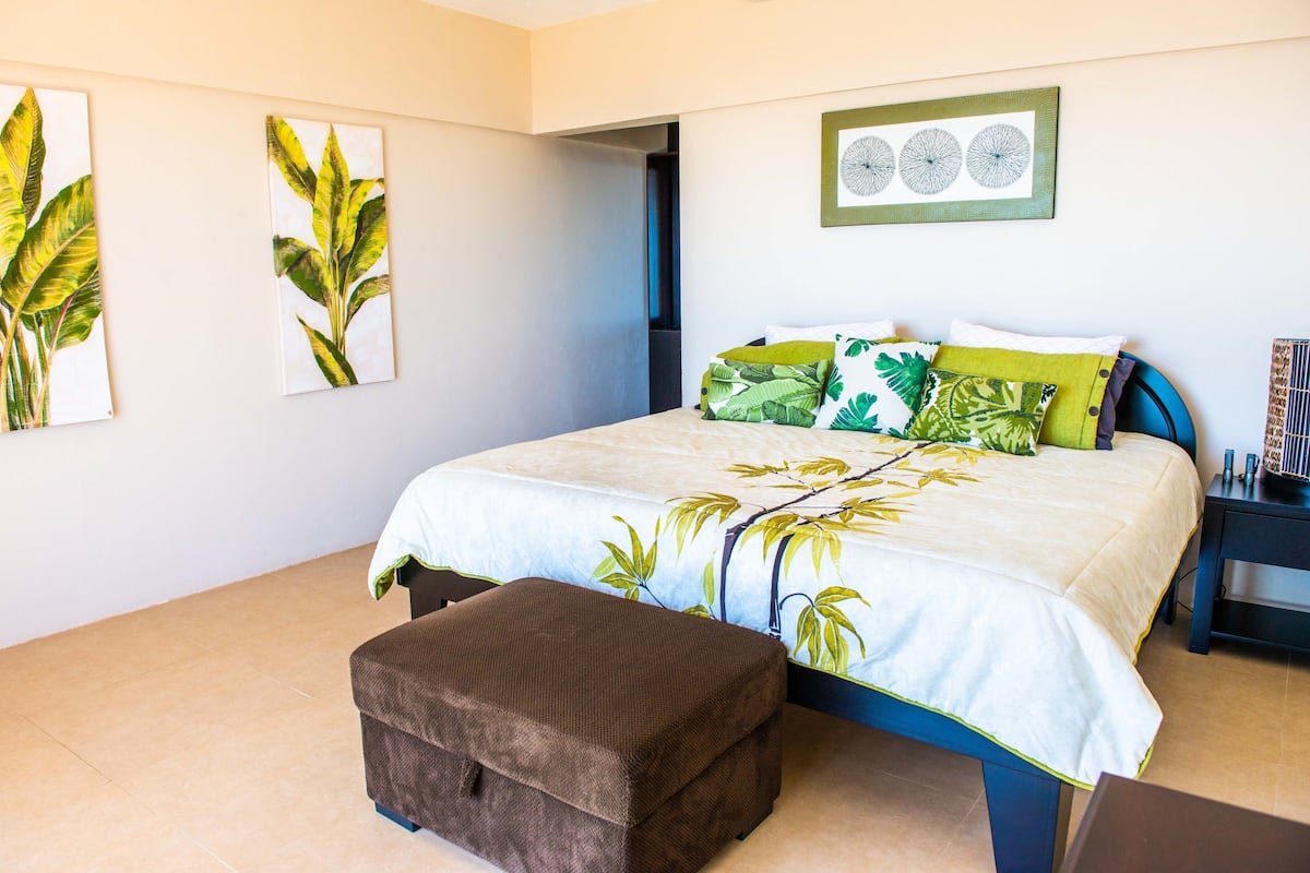 Un dormitorio con cama, un banco y decoración en la pared.