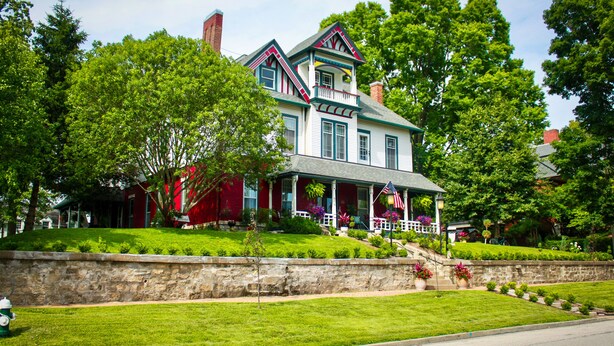 A large, two-story house with a porch, surrounded by lush green lawns and trees. - Evans Holly Grove Inn B&B (Burlington)