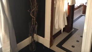 A hallway with a black wall, a white vase with branches, and two white robes hanging on a rack. - Evans Holly Grove Inn B&B (Burlington)