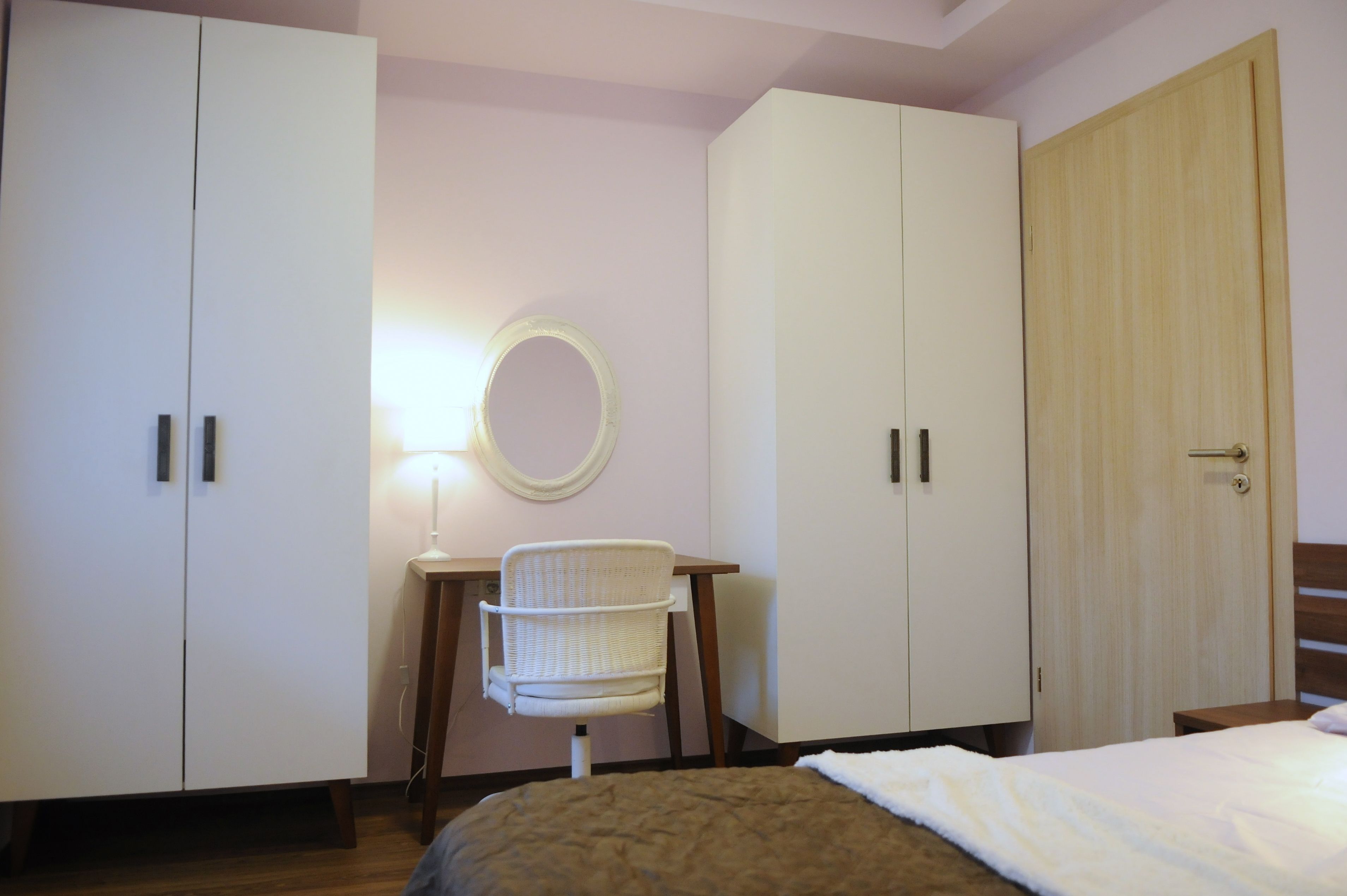 Un dormitorio con cama, escritorio con silla, armario y espejo.