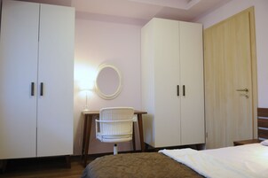 Un dormitorio con cama, escritorio con silla, armario y espejo.