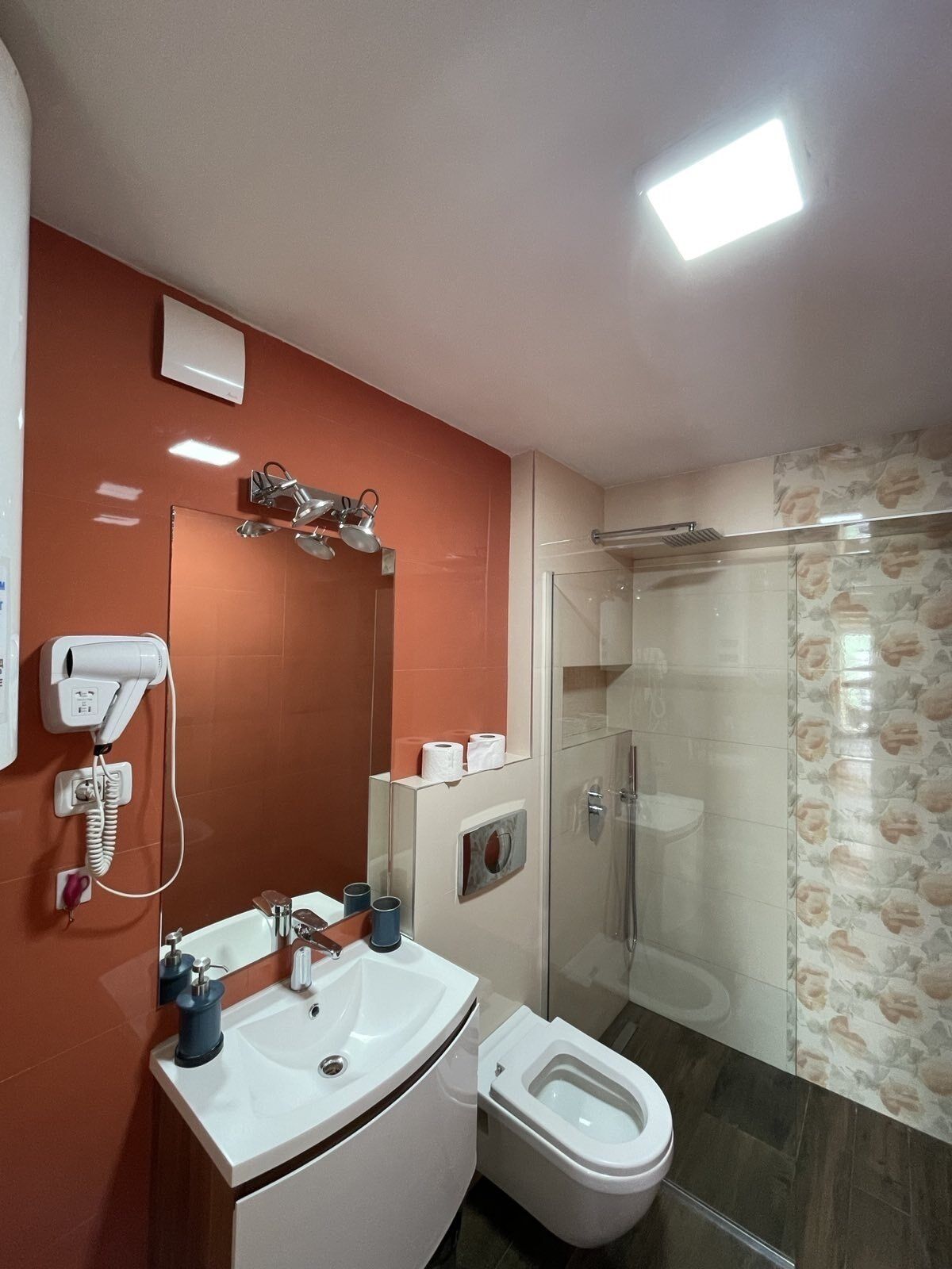 A modern bathroom with a white sink, a toilet, and a glass shower enclosure.