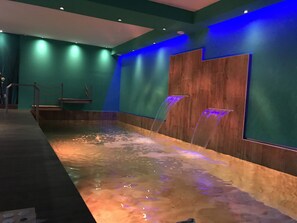 A spa area with a hot tub, wooden wall panels, and a blue-lit ceiling.