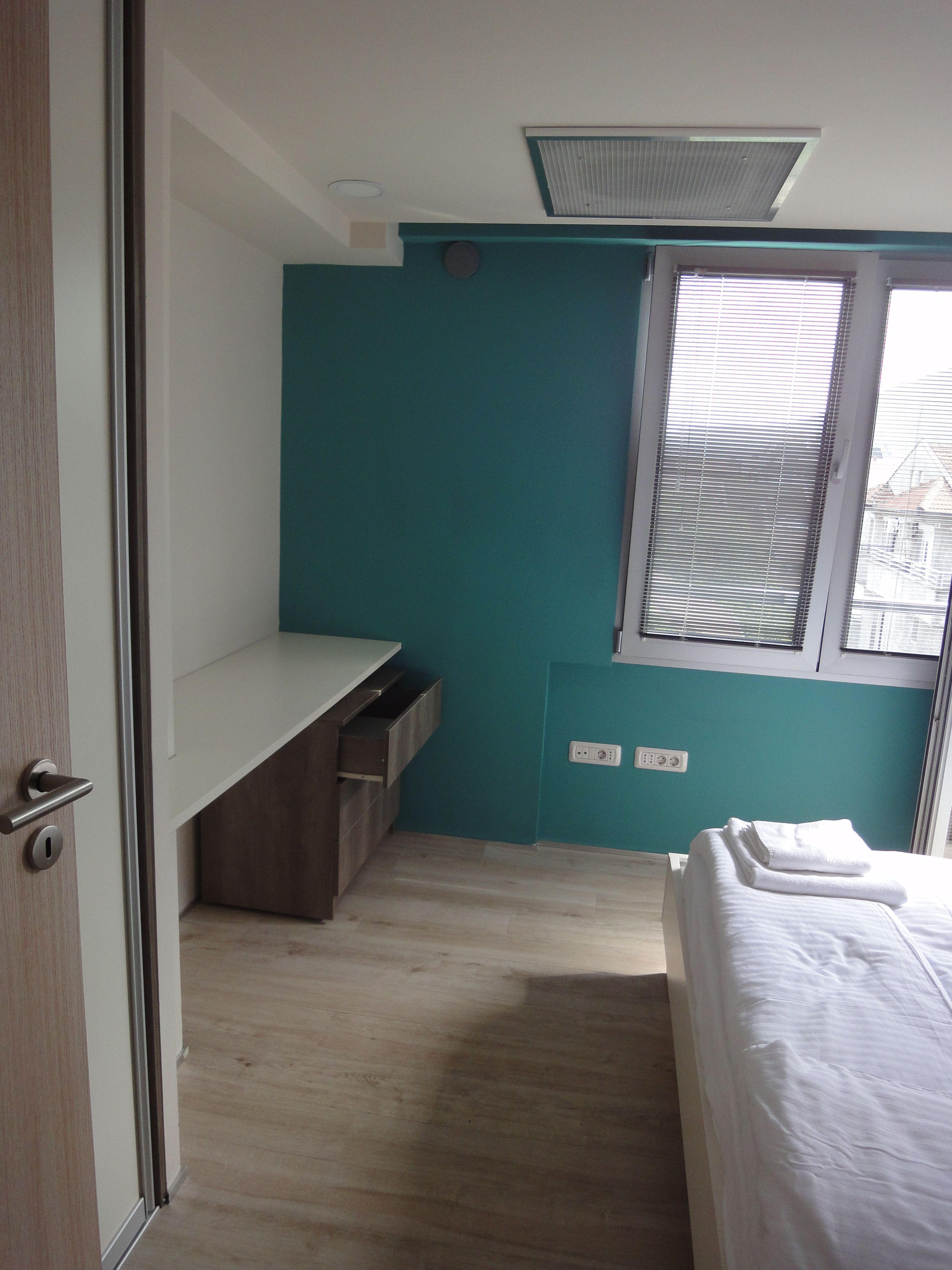 Ein Schlafzimmer mit einem Bett, einem Schreibtisch und einem Fenster.