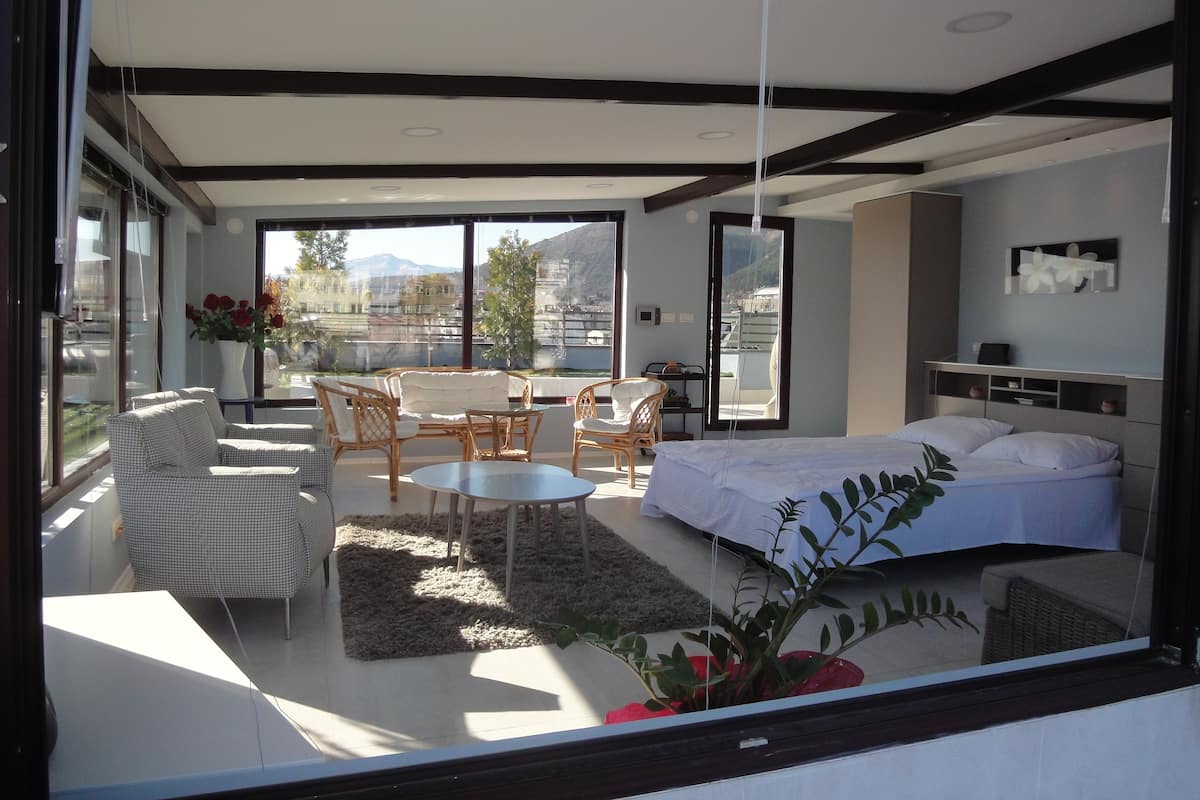 A modern bedroom with a large bed, a sofa, and a dining area.