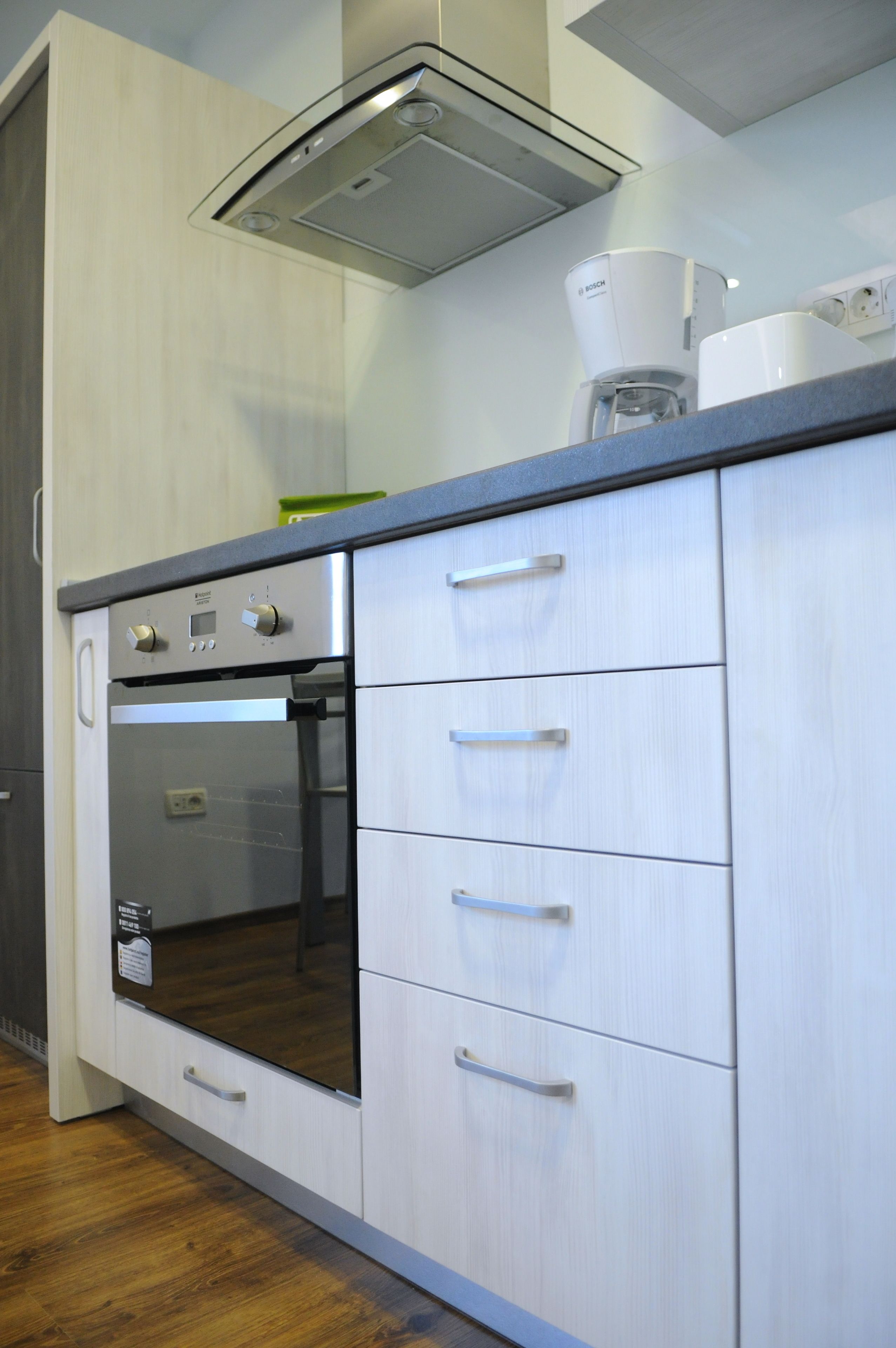 A kitchen with a built-in oven, a coffee maker, and a range hood.