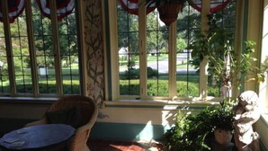 A sunlit room with wicker furniture, a potted plant, and a statue.