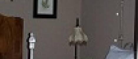 A bedroom with a bed, bedside table, lamp, and a framed picture on the wall.