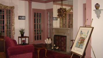 A room with a fireplace, a red armchair, a small table, and a painting on an easel.