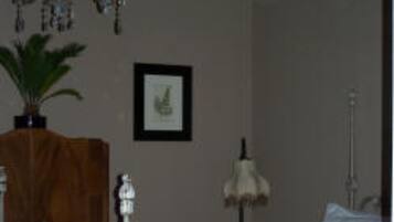 A bedroom with a large bed, a chandelier, a wooden cabinet, a framed picture, and a lamp.
