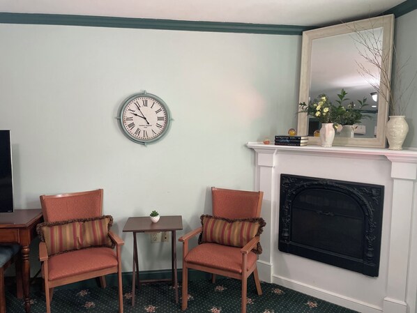 A living room with two armchairs, a small table, a clock, a fireplace, and a mirror above it. - Hargrave House B & B (Doylestown)