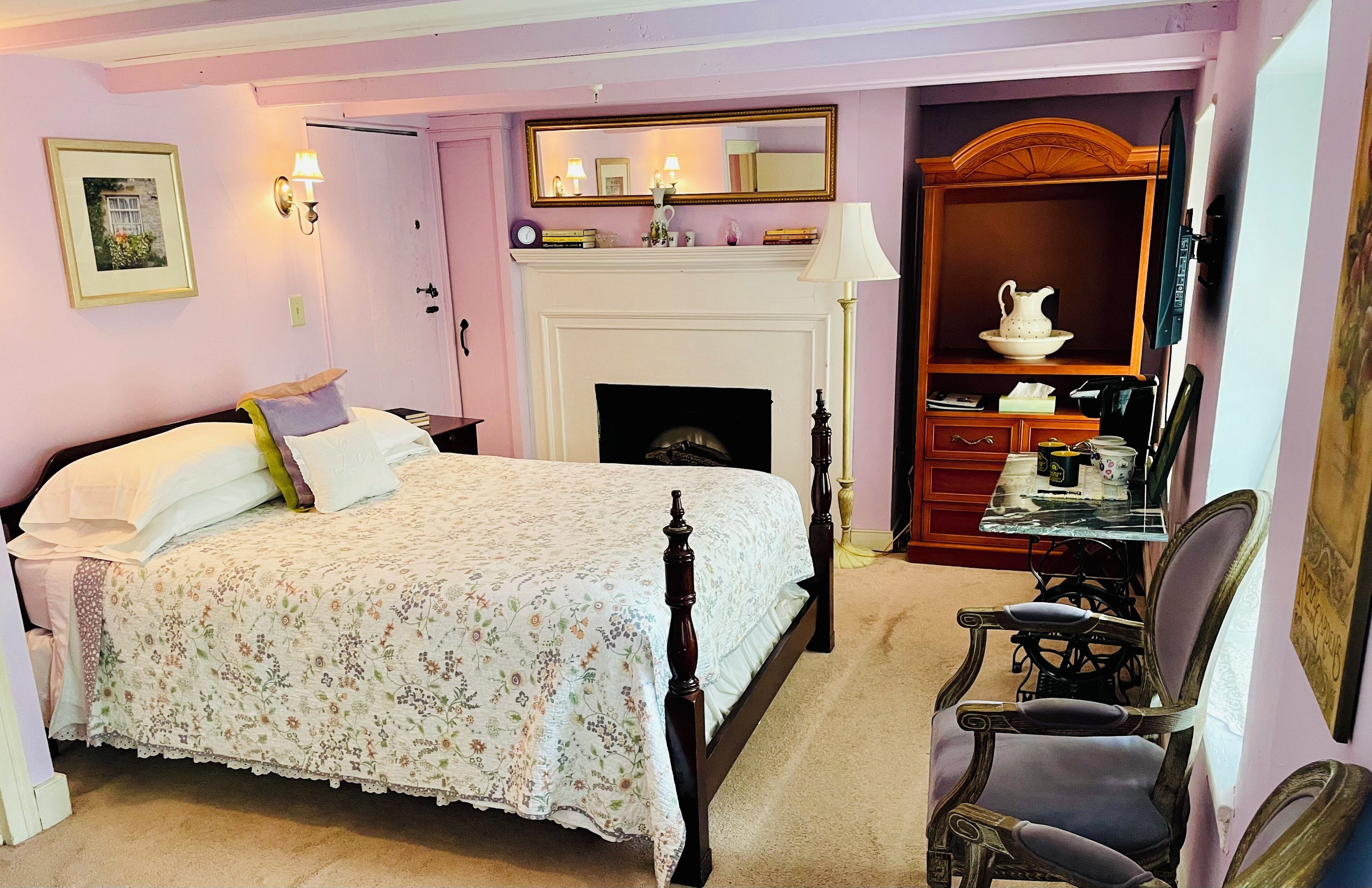 Une chambre à coucher avec un lit à baldaquin, une cheminée, une armoire en bois et un bureau avec une chaise.