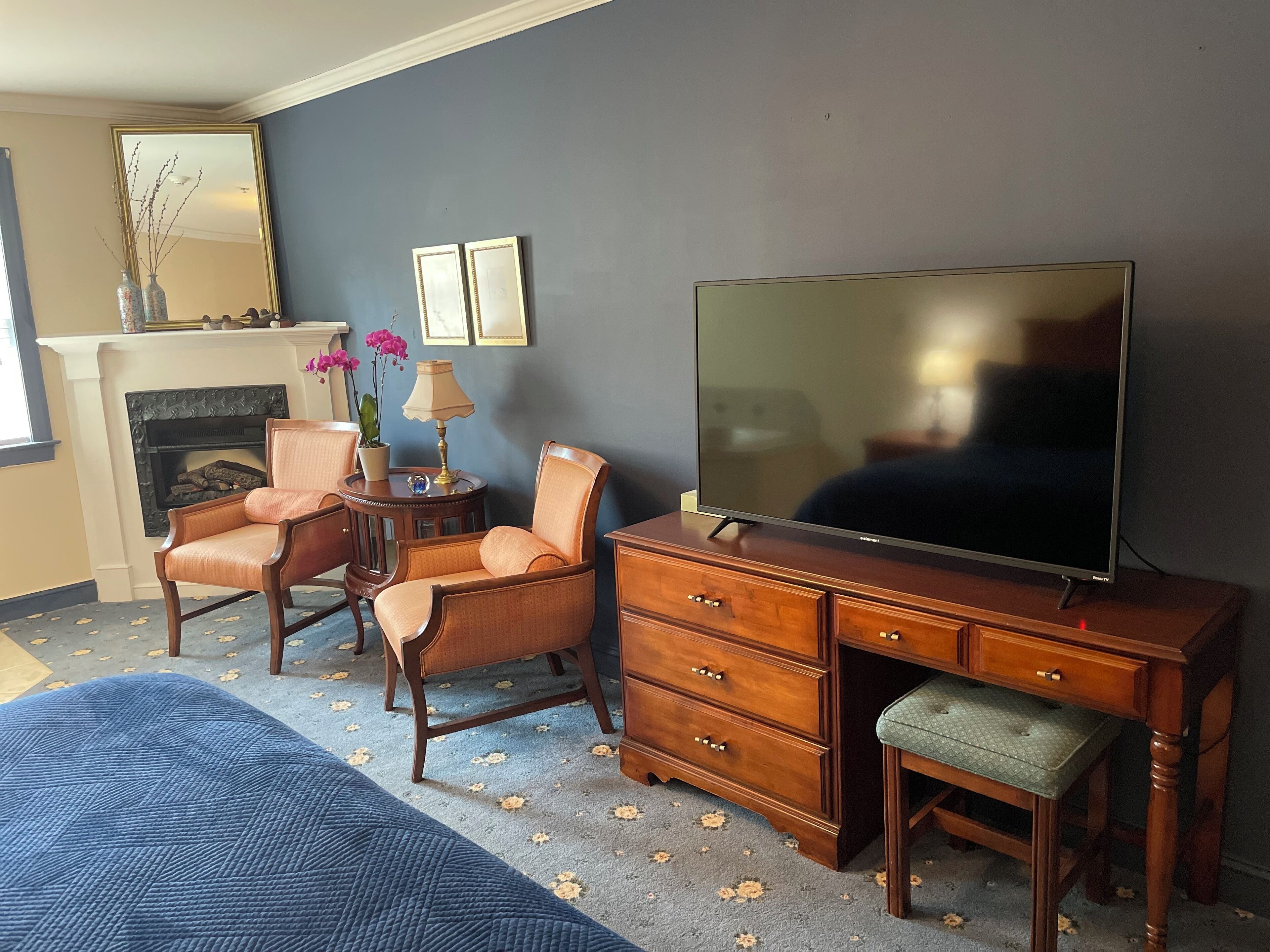 Una sala de estar con televisor, dos sillones, chimenea y alfombra azul.