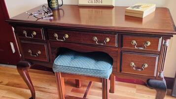 Un escritorio de madera con cajones, una silla con cojín azul, un letrero que dice "Hargrove House ca. 1814" y un libro sobre el escritorio.