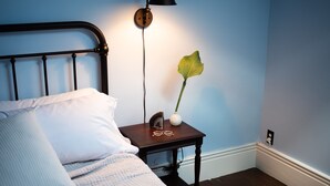 Une chambre à coucher avec un lit, une table de chevet, une lampe et une plante.