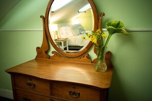 A wooden dresser with a mirror, a vase with yellow flowers, and a green wall. - Black Walnut Bed and Breakfast (Interlaken)