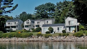 A row of modern, multi-story houses with balconies, situated by a body of water, surrounded by trees. - Dockside Guest Quarters & Restaurant (York)