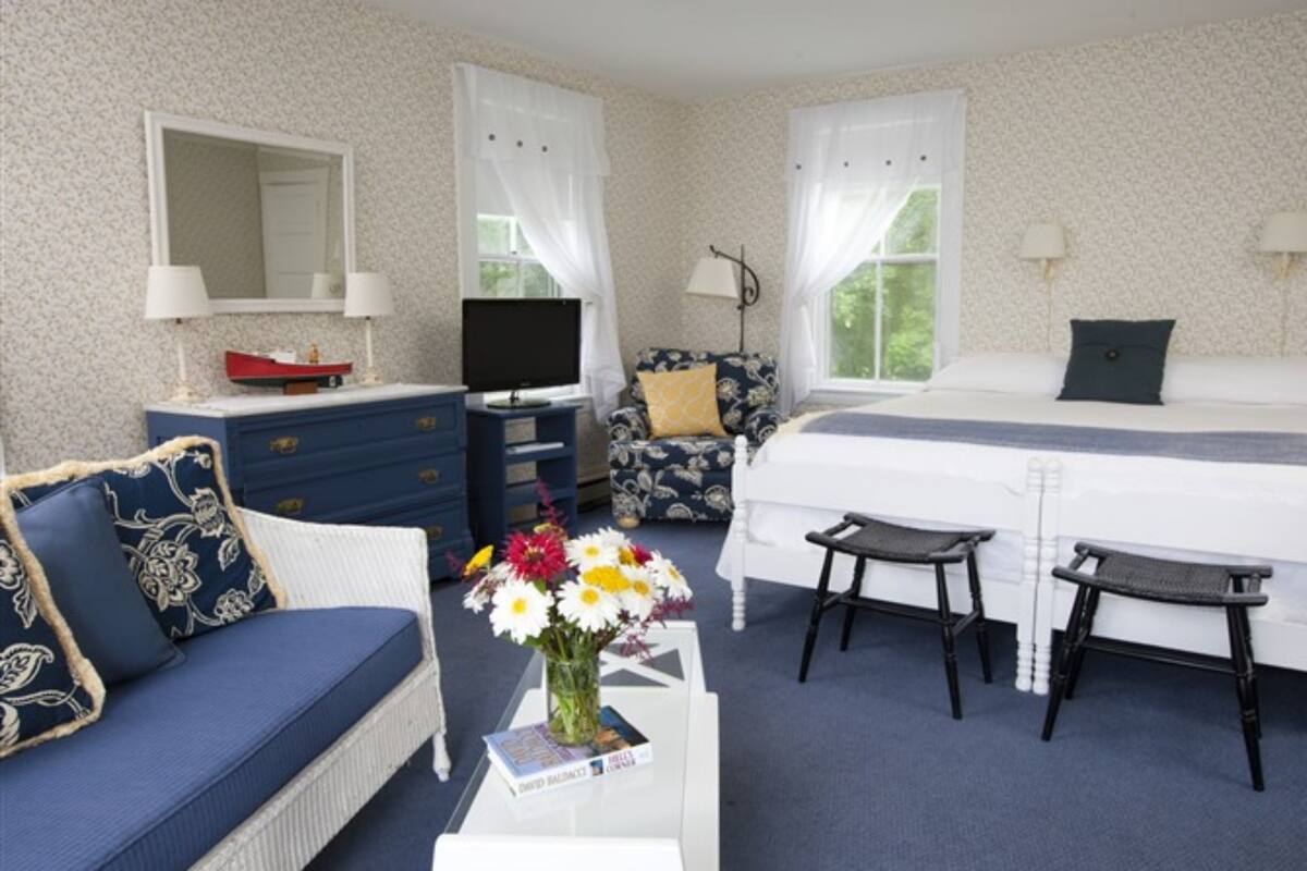 A bedroom with a bed, a sofa, a television, a dresser, and a chair.