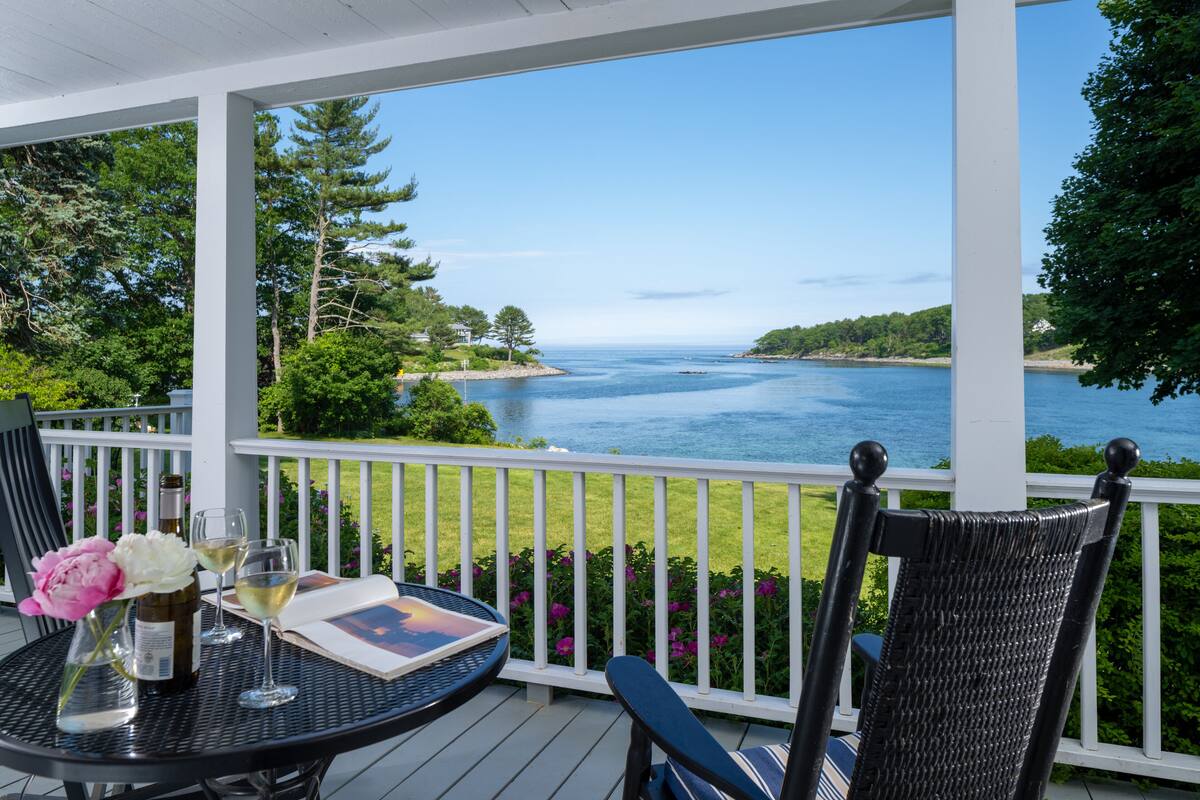 A covered outdoor area with a table, chairs, and a view of a body of water.