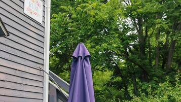 A gray house with a porch, a purple umbrella, and colorful outdoor furniture.